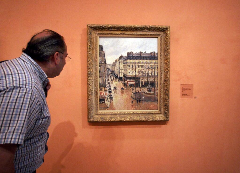 FILE- This May 12, 2005 file photo shows an unidentified visitor viewing the Impressionist painting called 'Rue St.-Honore, Apres-Midi, Effet de Pluie' painted in 1897 by Camille Pissarro, on display in the Thyssen-Bornemisza Museum in Madrid. A Jewish woman's acceptance of a settlement from the German government for the Pissarro painting looted from her by the Nazis did not bar her grandchildren from suing to try to get the masterpiece back, a U.S. federal appeals court said Monday, July 10, 2017. (AP Photo/ Mariana Eliano, File)