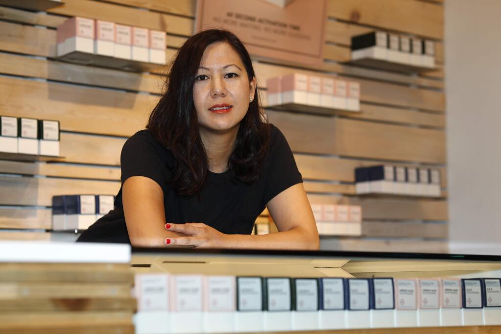 In this Friday, July 26, 2019 photo, Leslie Siu poses for a portrait next to her cannabis products geared toward women on display in Groundswell dispensary in east Denver. Pregnancy started out rough for her. Morning sickness and migraines had her reeling and barely able to function at a demanding New York marketing job, so like rising numbers of U.S. mothers-to-be, she turned to marijuana. “l was finally able to get out from under my work desk,” said Siu, who later started her own pot company and says her daughter, now 4, is thriving. (AP Photo/David Zalubowski)
