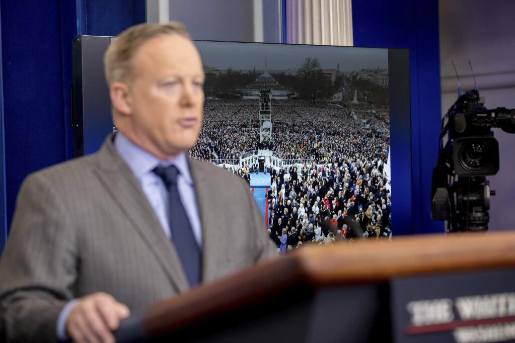 An image of the inauguration of President Donald Trump is displayed behind Press Secretary Sean Spicer as he speaks at the White House on Saturday. (ANDREW HARNIK / Associated Press)