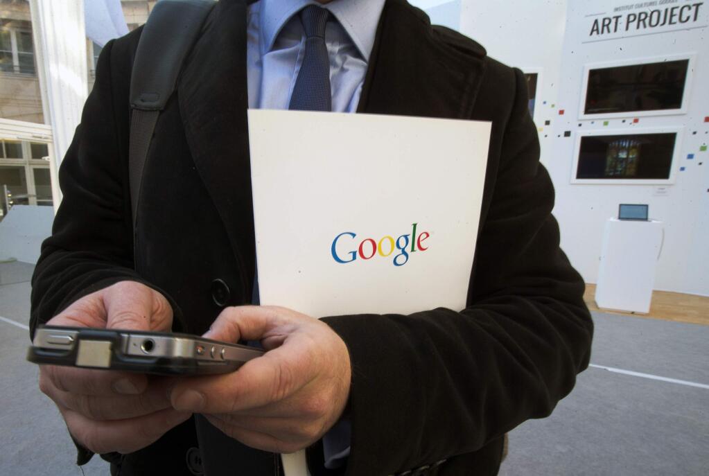 FILE - In this Dec. 10, 2013 file photo, a reporter uses his smartphone during a presentation for the new Google cultural institute in Paris. More Google search requests are now being made on mobile devices than personal computers in the U.S. and many other parts of the world. The milestone was announced at a digital advertising conference on Tuesday, May 5, 2015. (AP Photo/Jacques Brinon, File)