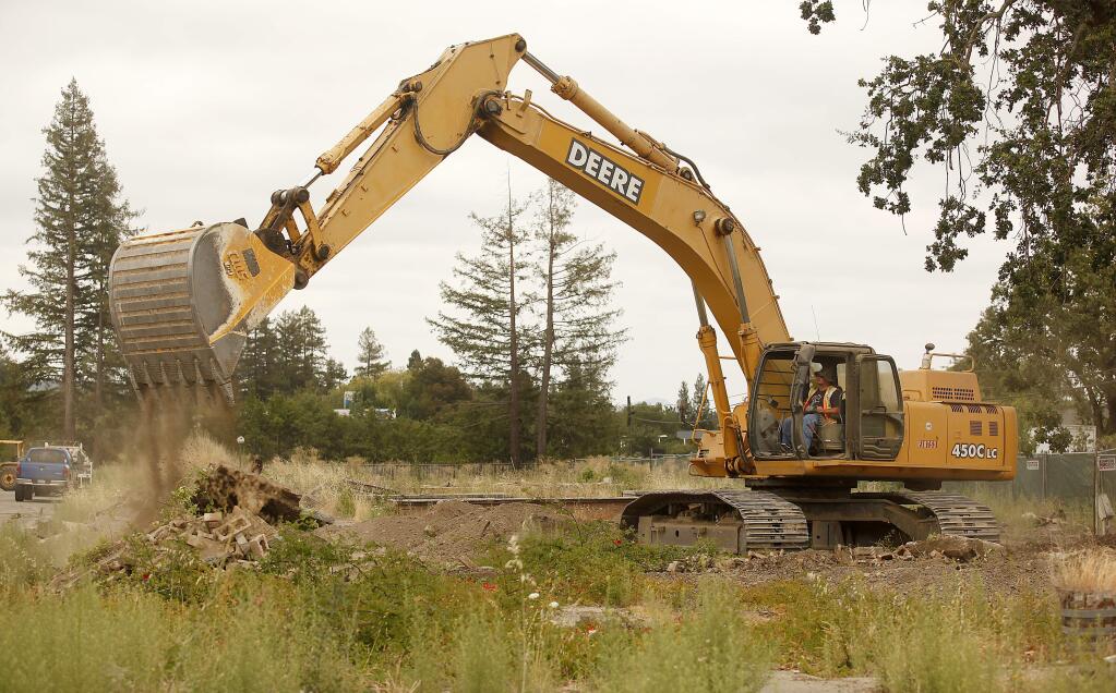 Adin Hall of Northwest General Engineering clears debris with an excavator on the construction site where the new Oliver's Market is being built in Windsor on Old Redwood Highway, Tuesday, August 12, 2014. (Crista Jeremiason / The Press Democrat)