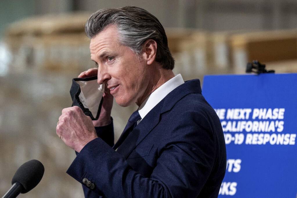 Gov. Gavin Newsom removes his face mask before speaking at a press conference to announce the next phase of California's COVID-19 response called “SMARTER,” at the UPS Healthcare warehouse in Fontana, Calif., Thursday, Feb. 17, 2022. (Watchara Phomicinda/The Orange County Register/SCNG via AP)