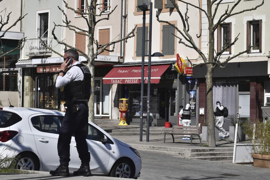 A police officer gives a phone call after a man wielding a knife attacked residents venturing out to shop in the town under lockdown, Saturday April 4, 2020 in Romans-sur-Isere, southern France. The alleged attacker was arrested by police nearby, shortly after the attack. Prosecutors did not identify him. They said he had no documents but claimed to be Sudanese and to have been born in 1987. (AP Photo)