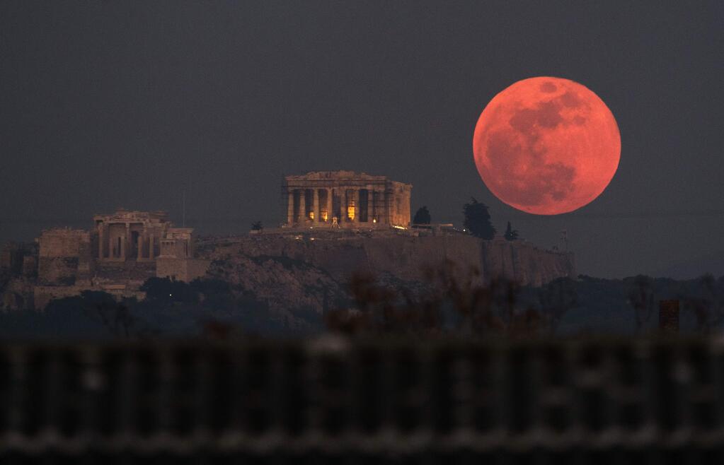 A super blue blood moon rises Jan. 31 behind the 2,500-year-old Parthenon temple on the Acropolis of Athens. (PETROS GIANNAKOURIS / Associated Press)