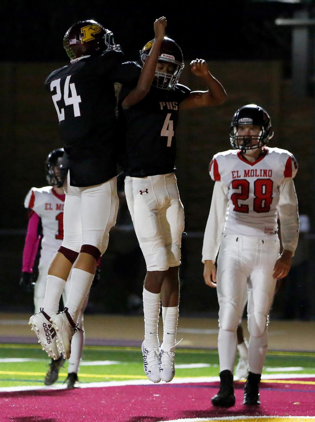 Piner's Adrian Torres, left, jumps together with Yonaton Isack to celebrate after Isack scored a touchdown, while El Molino's Soul Berna, far right, looks on, during the first half on Friday, Oct. 11, 2019. (Alvin Jornada / The Press Democrat)