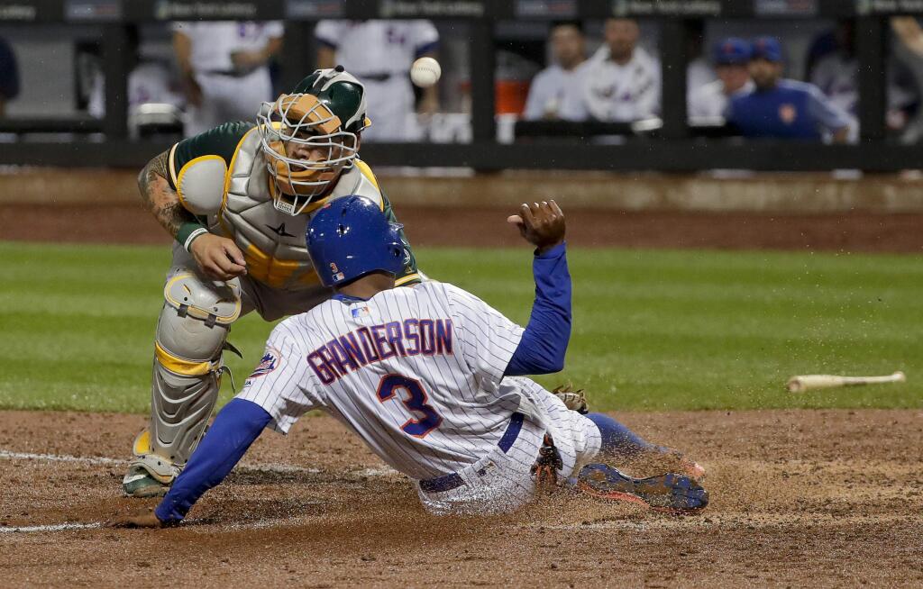 The New York Mets' Curtis Granderson slides safely into home plate as the ball skips away from Oakland Athletics catcher Bruce Maxwell during the sixth inning Saturday, July 22, 2017, in New York. Grandson scored on a double by Michael Conforto. (AP Photo/Julie Jacobson)