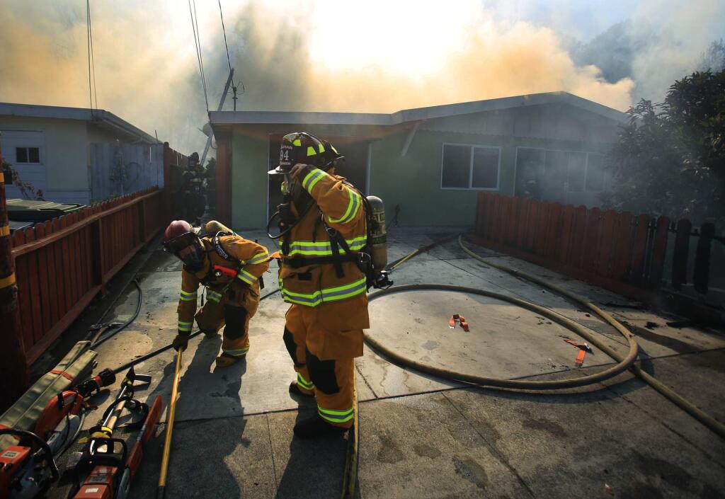 Wilmar firefighters prepare to enter a burning home on Stuart Drive in Petaluma, stemming from a brush fire that damaged 13 homes and properties, Tuesday Sept. 27, 2016 parallel to Highway 101. (Kent Porter / The Press Democrat) 2016