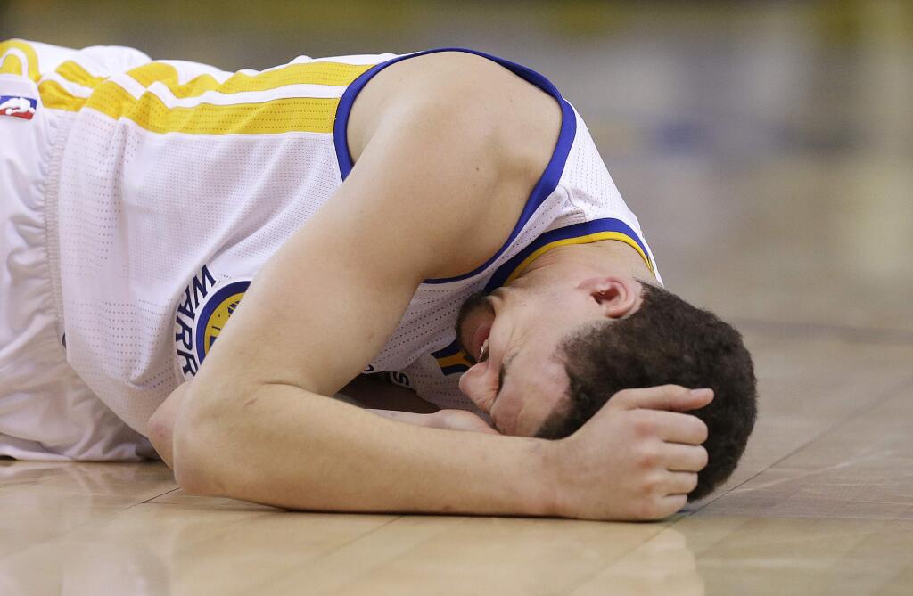 In this photo taken May 27, 2015, Golden State Warriors guard Klay Thompson reacts after taking a knee to his head from Houston Rockets forward Trevor Ariza during the second half of Game 5 of the NBA basketball Western Conference finals. The Warriors hope to get healthy and stay in tune over the next week before facing the Cleveland Cavaliers in the NBA Finals. Thompson needs to pass through the league's concussion protocol and Stepehen Curry is trying to get his aching body back at full strength. (AP Photo/Ben Margot)