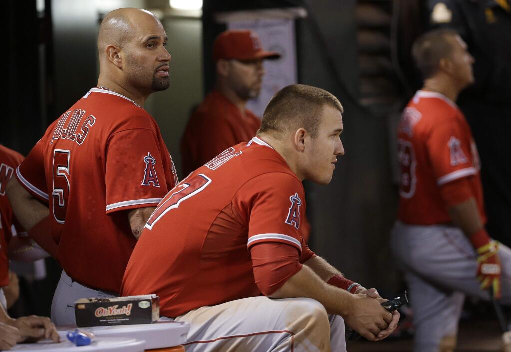 Los Angeles Angels first baseman Albert Pujols (5) and center fielder Mike Trout (27) sit in the dugout during the fifth inning of a baseball game against the Oakland Athletics on Tuesday, Sept. 1, 2015, in Oakland, Calif. (AP Photo/Jeff Chiu)