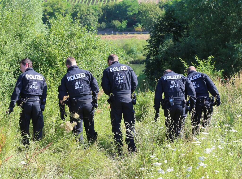 Police officers search for traces near the crime scene where a 17-year-old man from Afghanistan was shot the night before, in Wuerzburg, Germany, Tuesday, July 19, 2016. On Monday evening, the man wielding an axe and knife attacked travelers on a regional train near Wuerzburg. Four people were seriously injured. He was shot and killed by police as he fled. (Karl-Josef Hildenbrand/dpa via AP)