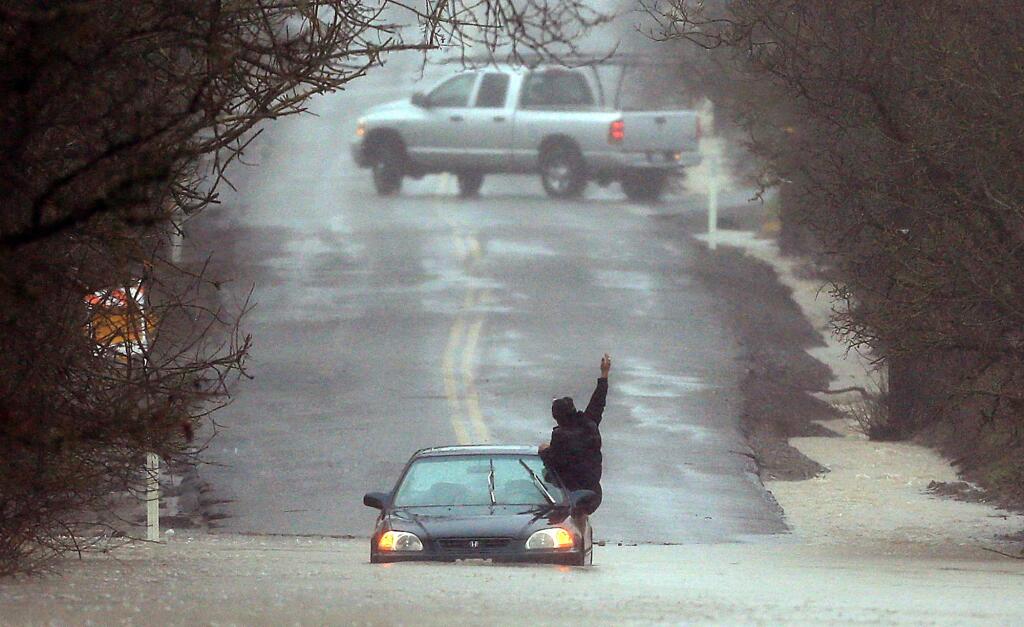 A motorist tries to catch someone's attention after driving into floodwaters at Mark West Station Road in Windsor, Wednesday Jan. 18, 2017. After several 911 calls from others on the scene, a good Samaritan pulled him out to dry ground. (Kent Porter / The Press Democrat) 2017