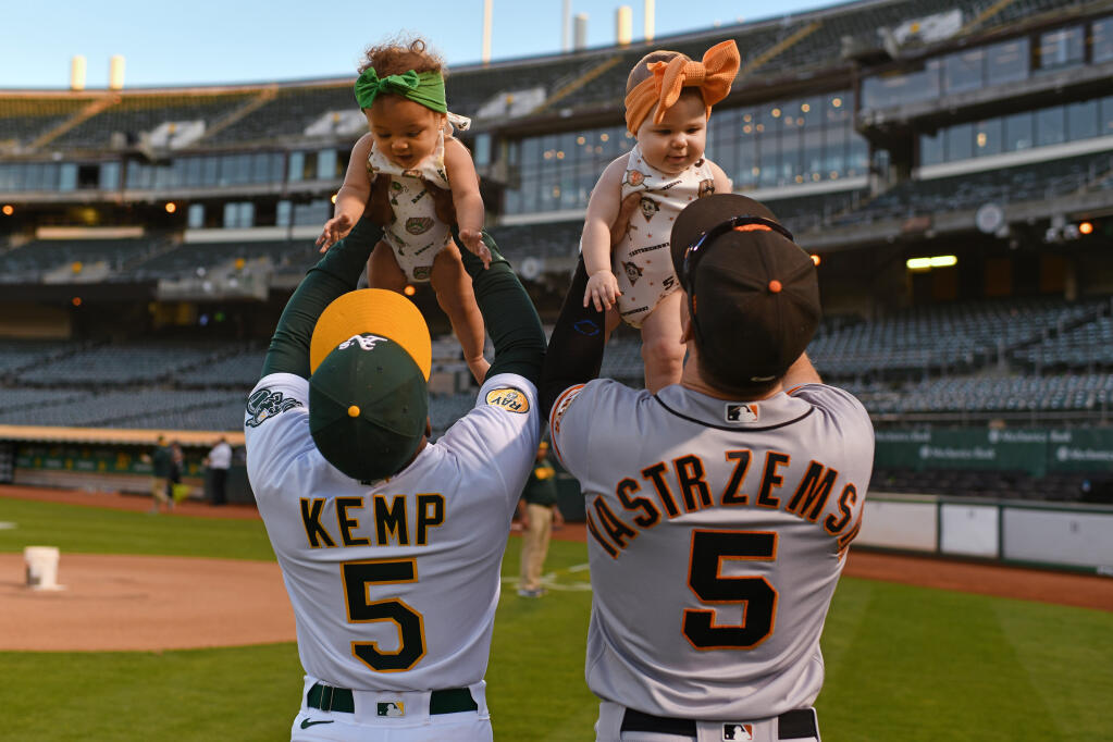 The A’s Tony Kemp holds his daughter McKenna, 7 months, and The Giants’ Mike Yastrzemski holds his daughter Quinley, 8 months, after their game Saturday, Aug. 6, 2022, in Oakland. Both players played baseball together at Vanderbilt. (Jose Carlos Fajardo / SAN JOSE MERCURY NEWS)
