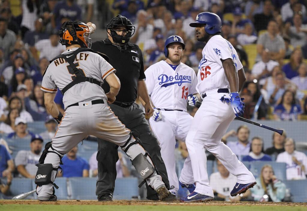 San Francisco Giants catcher Nick Hundley, left, reacts to being shoved by Los Angeles Dodgers' Yasiel Puig, right, as they argue while home plate umpire Eric Cooper, second from left, gets between them and Max Muncy runs in during the seventh inning Tuesday, Aug. 14, 2018, in Los Angeles. (AP Photo/Mark J. Terrill)