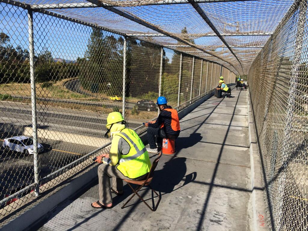 Wearing hard hats, safety vests and even a gas mask in one case, workers on a Santa Rosa overpass have stoked curiosity and at least one complaint. A two-day study by the Metropolitan Transportation Commission wrapped up Thursday, May 28, 2015. (Photo by Clark Mason / The Press Democrat)