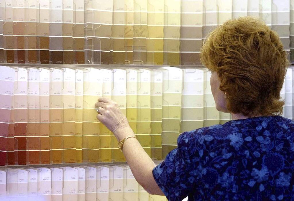 FILE - In this June 28, 2004, file photo, a customer looks over color chips at a Sherwin-Williams store in Columbus, Ohio. The nation's major suppliers of lead paint have agreed to pay California's largest cities and counties $305 million to settle a nearly two-decade old lawsuit. The settlement announced Wednesday, July 17, 2019, comes after years of legal and legislative battling in California and other states. The settlement is with the Sherwin-Williams Company, ConAgra Grocery Products Company and NL Industries, Inc. (AP Photo/Jay LaPrete, File)