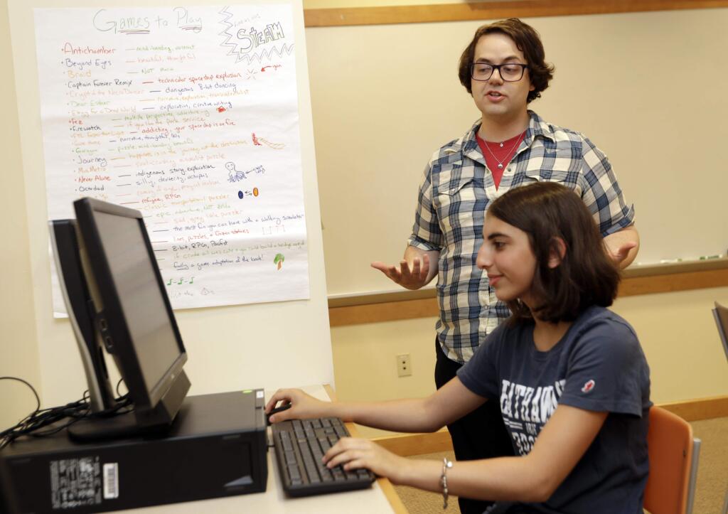 Coach J Collins watches Kaila Morris play 'Heroes of the Storm,' at Hathaway Brown School, Wednesday, July 10, 2019, in Shaker Heights, Ohio. Hathaway Brown launched the country's first varsity esports program at an all-girls school. Collins hopes to encourage more girls to stick with video games through their teenage years, something that might have a ripple effect across an industry grappling with gender disparity. (AP Photo/Tony Dejak)