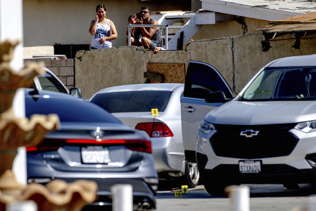 Residents watch as Riverside Police Department investigate the scene where a few people were fatally shot and one person was injured in an assault on Pierce Street in Riverside, Calif., on Wednesday, May 4, 2022. (Watchara Phomicinda/The Orange County Register/SCNG via AP)