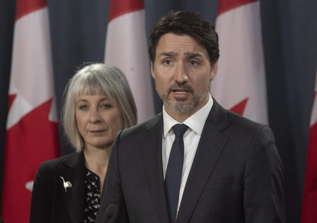 Minister of Health Patty Hajdu looks on as Prime Minister Justin Trudeau speaks during a news conference in Ottawa, Wednesday March 11, 2020. Canada is announcing $1 billion ($730 million) in funding to help health-care workers cope with the increasing number of new cases of coronavirus and to help Canadian workers who are forced to isolate themselves. (Adrian Wyld/The Canadian Press via AP)