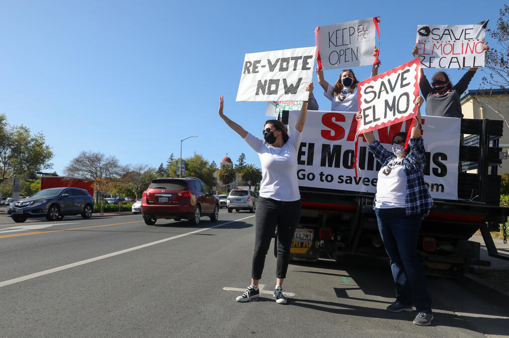 Opponents to the consolidation of El Molino and Analy high schools wave signs at traffic along North Main Street in Sebastopol on Thursday, April 8, 2021.  (Christopher Chung/ The Press Democrat)