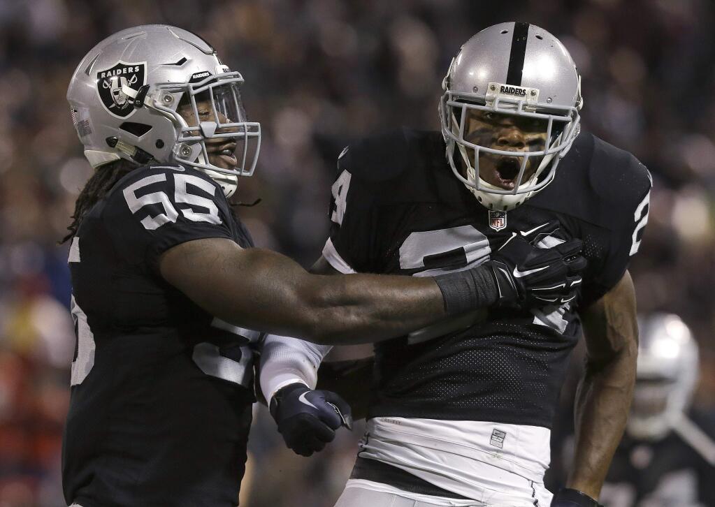 Oakland Raiders cornerback Charles Woodson (24) celebrates with outside linebacker Sio Moore (55) after tackling Kansas City Chiefs running back Jamaal Charles during the first quarter of an NFL football game in Oakland, Calif., Thursday, Nov. 20, 2014. (AP Photo/Jeff Chiu)