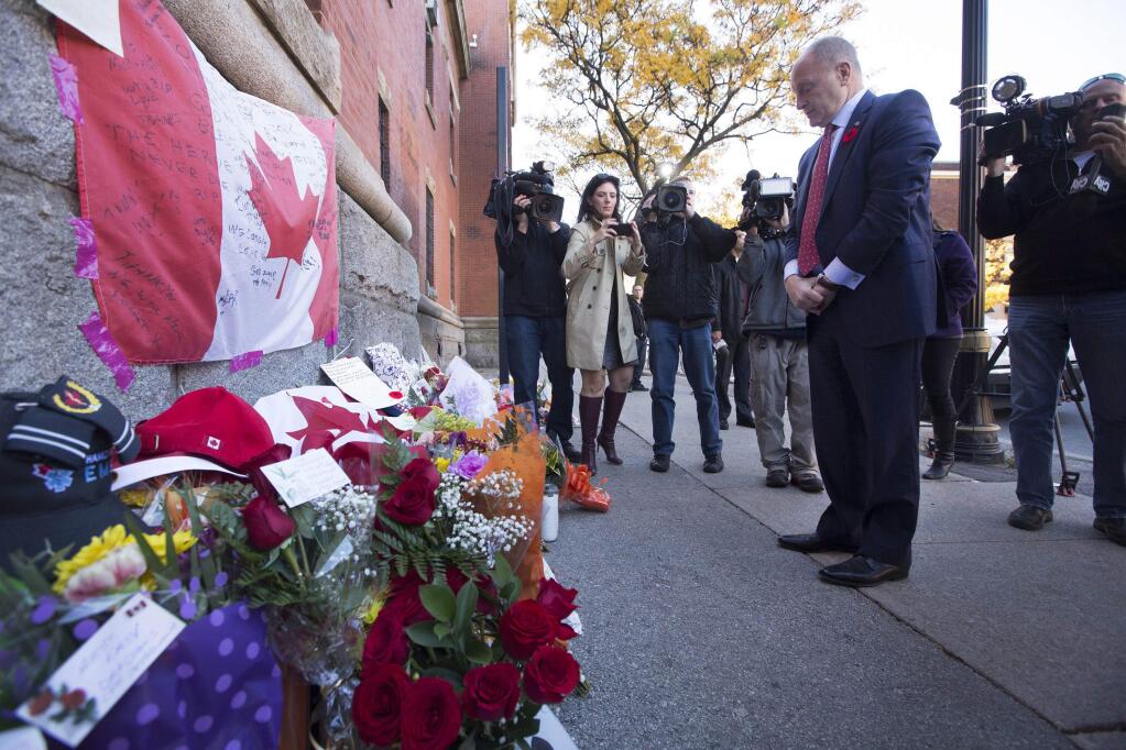 Bruce Heyman, the American ambassador to Canada, pays his respects at a makeshift memorial to Cpl. Nathan Cirillo outside of The Lieutenant-Colonel John Weir Foote Armory in Hamilton, Ontario on Thursday, Oct. 23, 2014. Cirillo was shot dead at the National War Memorial by Michael Zehaf Bibeau on Wednesday. Bibeau was killed in Parliament Hill, just feet from where hundreds of MPs were meeting for their weekly caucus meetings. (AP Photo/The Canadian Press, Peter Power)