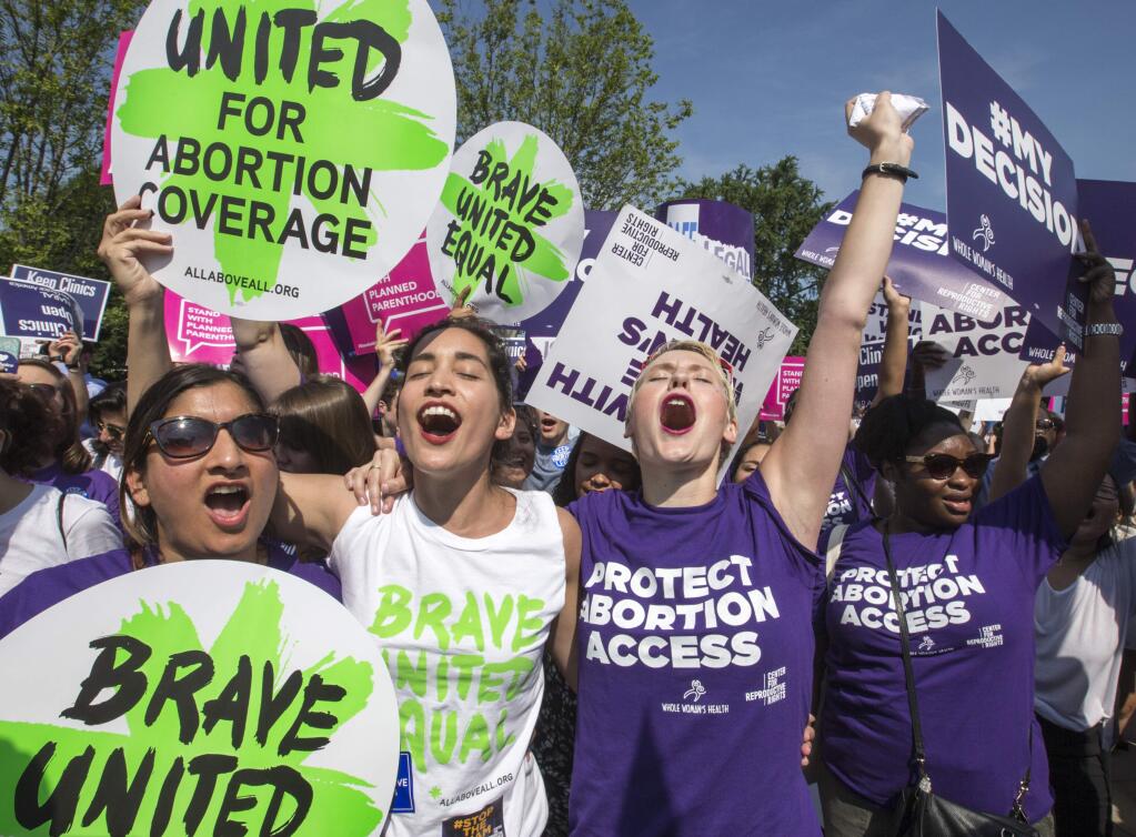 Abortion rights activists, from left, Ravina Daphtary of Philadelphia, Morgan Hopkins of Boston, and Alison Turkos of New York City, rejoice in front of the Supreme Court in Washington, Monday, June 27, 2016, as the justices struck down the strict Texas anti-abortion restriction law known as HB2. Other cases are to follow on guns, and public corruption. (AP Photo/J. Scott Applewhite)