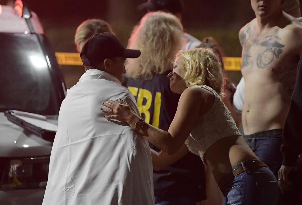 People comfort each other as they stand near the scene Thursday, Nov. 8, 2018, in Thousand Oaks, Calif. where a gunman opened fire Wednesday inside a country dance bar crowded with hundreds of people on 'college night,' wounding 11 people including a deputy who rushed to the scene. Ventura County sheriff's spokesman says gunman is dead inside the bar. (AP Photo/Mark J. Terrill)