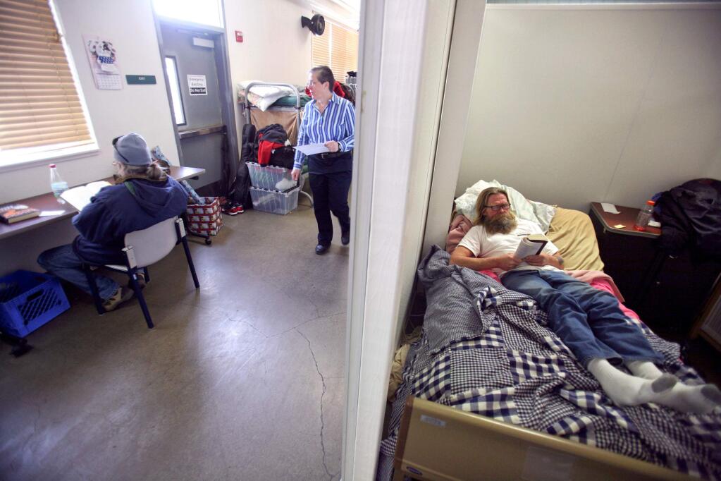 Shelter manager Robin Phoenix walks through a dorm room while Ron Pickering, right, and Harold Barrios read at COTS' Mary Isaak Center in Petaluma on Monday January 5, 2015. (SCOTT MANCHESTER/ARGUS-COURIER STAFF)