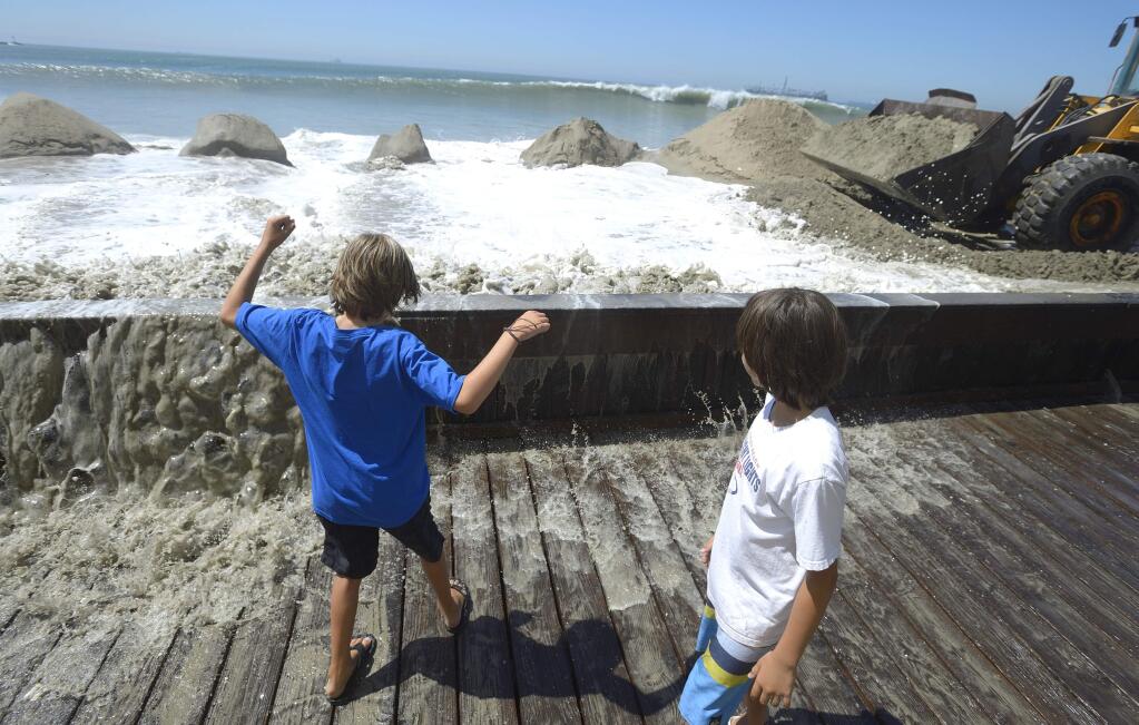 Davin Galinto, left, and Dorian Ortloff recoil from a wave crashing against the board way on the Peninsula in Long Beach, Calif. during high tide on Wednesday, Aug. 27, 2014. Hurricane Marie in the Pacific Ocean west of Mexico has caused higher than normal surf along the Southern California coast Wednesday. (AP Photo/Orange County Register, Jeff Gritchen)