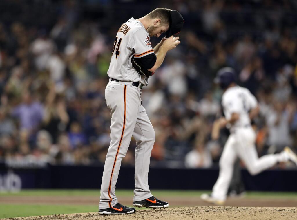 San Francisco Giants starting pitcher Chris Stratton, center, adjusts his cap as the San Diego Padres' Wil Myers, right, rounds the bases after hitting a two-run home run during the second inning Wednesday, Sept. 19, 2018, in San Diego. (AP Photo/Gregory Bull)