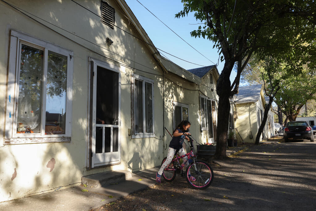 A young girl rides her bike at her family's apartment along McCray Road and North Redwood Highway in Cloverdale on Tuesday, Oct. 12, 2021.  (Christopher Chung / The Press Democrat)