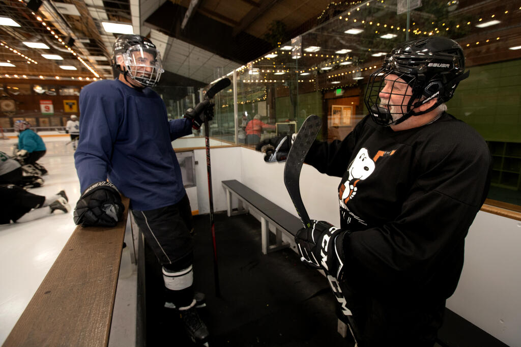 Phil LeBrun, right, talks with Mike Behler, both of Santa Rosa, both who are part of a hockey group who were friends of Charles Schulz, as they take a break from action in a hockey game called “Sparky’s Skate” at Snoopy’s Home Ice, in Santa Rosa, Tuesday, March 19, 2024. (Darryl Bush / For The Press Democrat)