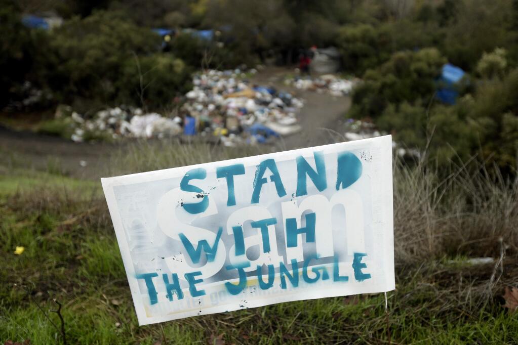 A sign in support of The Jungle is posted at the Silicon Valley homeless encampment, Monday, Dec. 1, 2014, in San Jose, Calif. City officials began posting notices on hand built structures, tents and tree trunks warning the 200 residents of what is likely the nation's largest homeless encampment that the bulldozers are coming. People living in the Silicon Valley camp, known as The Jungle, must be out by Thursday, Dec. 4 or face arrest for trespassing. (AP Photo/Marcio Jose Sanchez)
