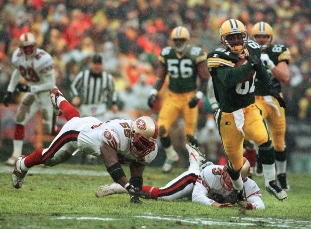 In this Jan. 4, 1997, file photo, the Green Bay Packers' Desmond Howard eludes San Francisco 49ers Kevin Mitchell and Tommy Thompson on the way to a touchdown on a punt return in the first half in Green Bay. (AP Photo/David Boe, File)