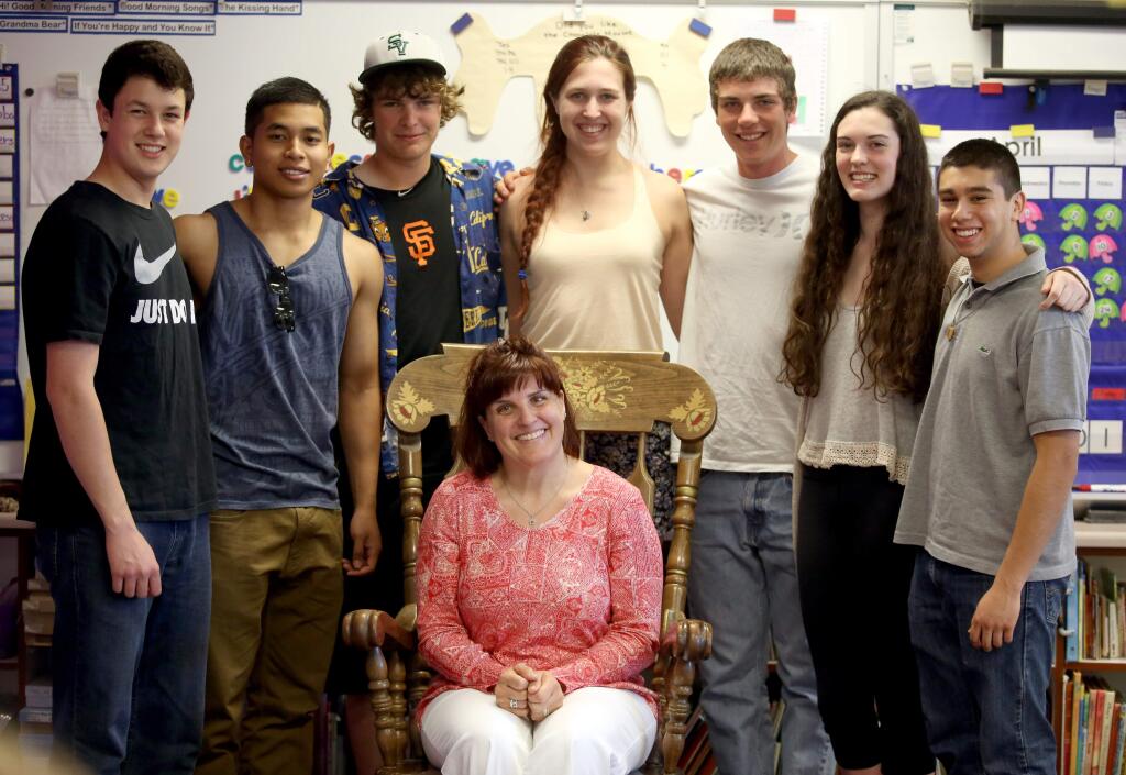 Sassarini Elementary teacher, Kim Tomasello, seated, taught kindergarten to a group of current graduating seniors who say that she had a big impact on their lives, Wednesday, April 29, 2015. The teens from left to right, Roberto Diaz, Chris Tith, Jack Hart, Ciara Smith, Thomas Crumly, Annie Thornton and Alexis Zamudio, got together for a small reunion in their old classroom. (CRISTA JEREMIASON / The Press Democrat)