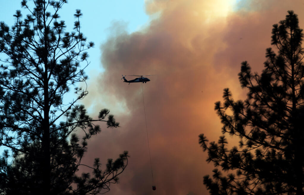 A helicopter drops water on the mountainside as the Rices Fire burns near French Corral, Calif., on Tuesday, June 28, 2022. (Carlos Avila Gonzalez/San Francisco Chronicle via AP)