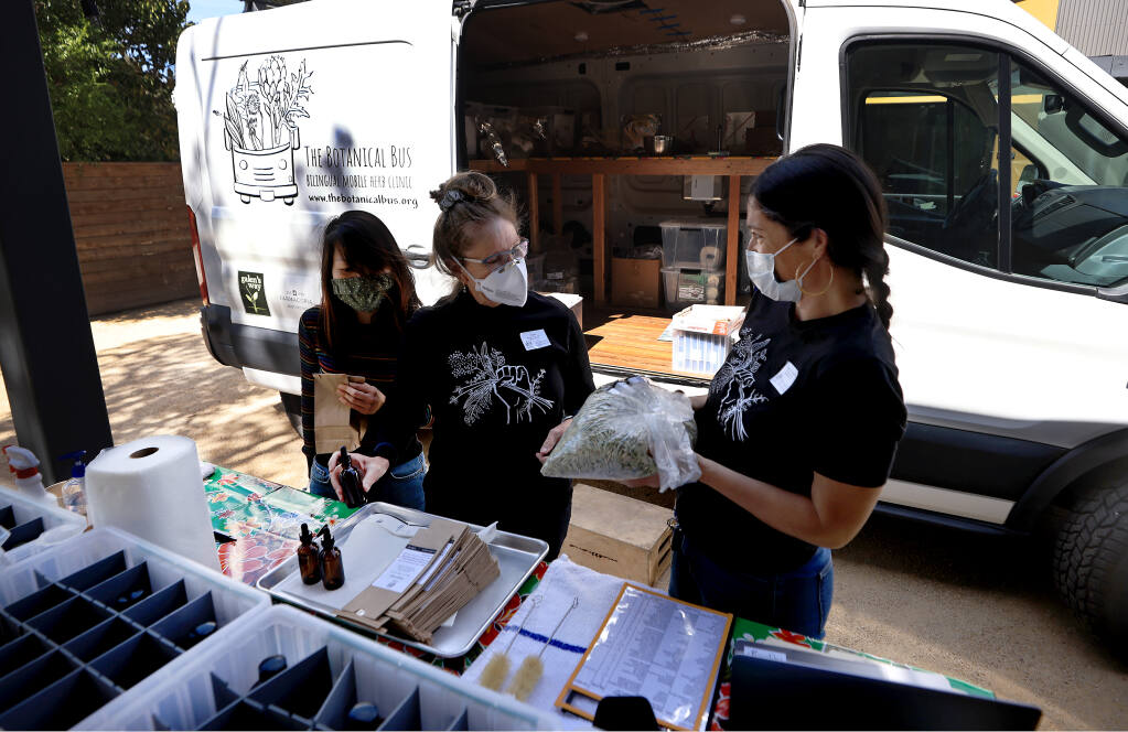 From left, Hao Le, Kim Lydon and Jocelyn Boreta, the director of the Botanical Bus, confer on the amount of herbs ready to package, Saturday, March 26, 2022.  The bus is a nonprofit mobile herb clinic, providing integrative health services to Latinx and indigenous clients.  The group was part of a clinic held at the La Luz Center in Sonoma.  (Kent Porter / The Press Democrat) 2022