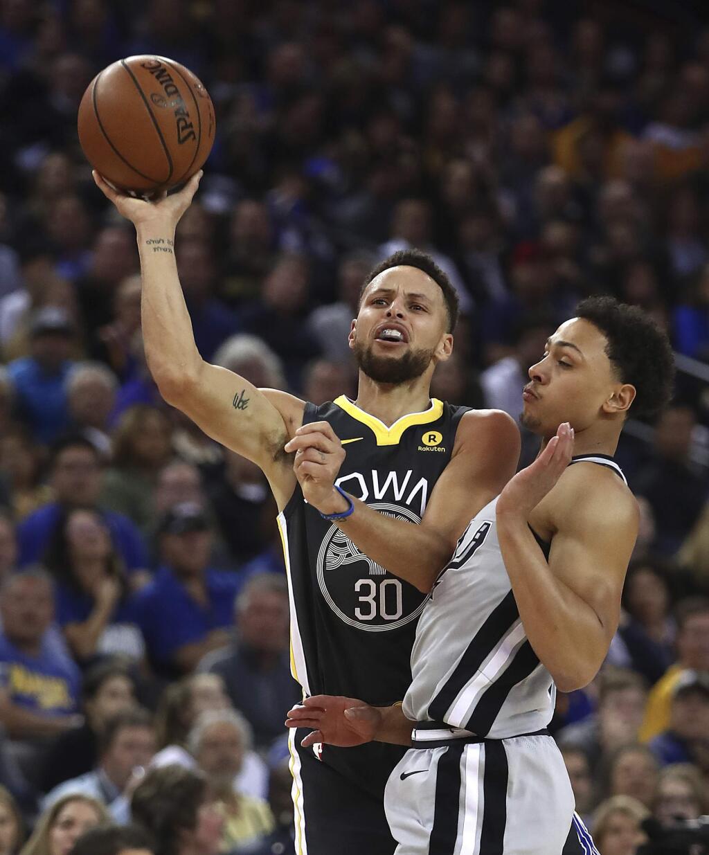 The Golden State Warriors' Stephen Curry, left, shoots over the San Antonio Spurs' Bryn Forbes during the first half Saturday, Feb. 10, 2018, in Oakland. (AP Photo/Ben Margot)