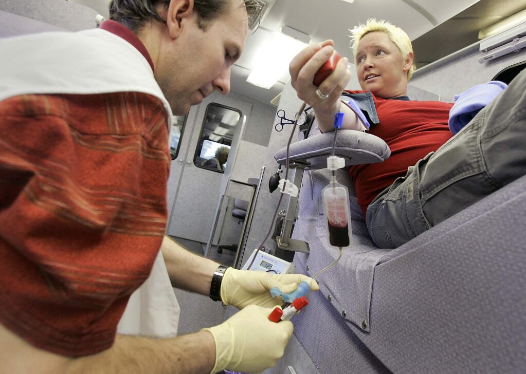 Melissa Minton, right, donates blood while phlebotomist Scott Godwin collects samples of her blood in vials, inside a Blood Bank of the Redwoods mobile unit at Community Market in Santa Rosa on Thursday, March 6, 2008. (CHRISTOPHER CHUNG/ PD FILE)