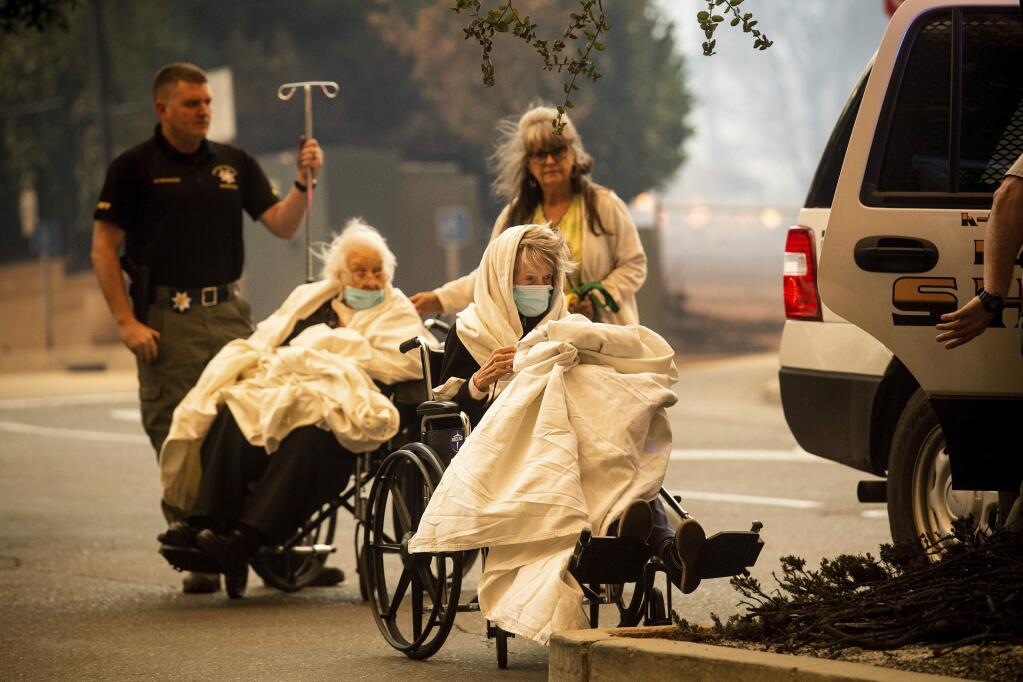 Emergency personnel evacuate patients as the Feather River Hospital burns while the Camp Fire rages through Paradise, Calif., on Thursday, Nov. 8, 2018. Tens of thousands of people fled a fast-moving wildfire Thursday in Northern California, some clutching babies and pets as they abandoned vehicles and struck out on foot ahead of the flames that forced the evacuation of an entire town. (AP Photo/Noah Berger)