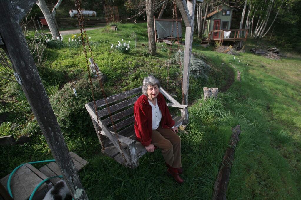 Ann Neel at her home in the hills above Guerneville, where a children's playhouse was transformed into her book-filled study next to her home. Books also line the bedroom walls.