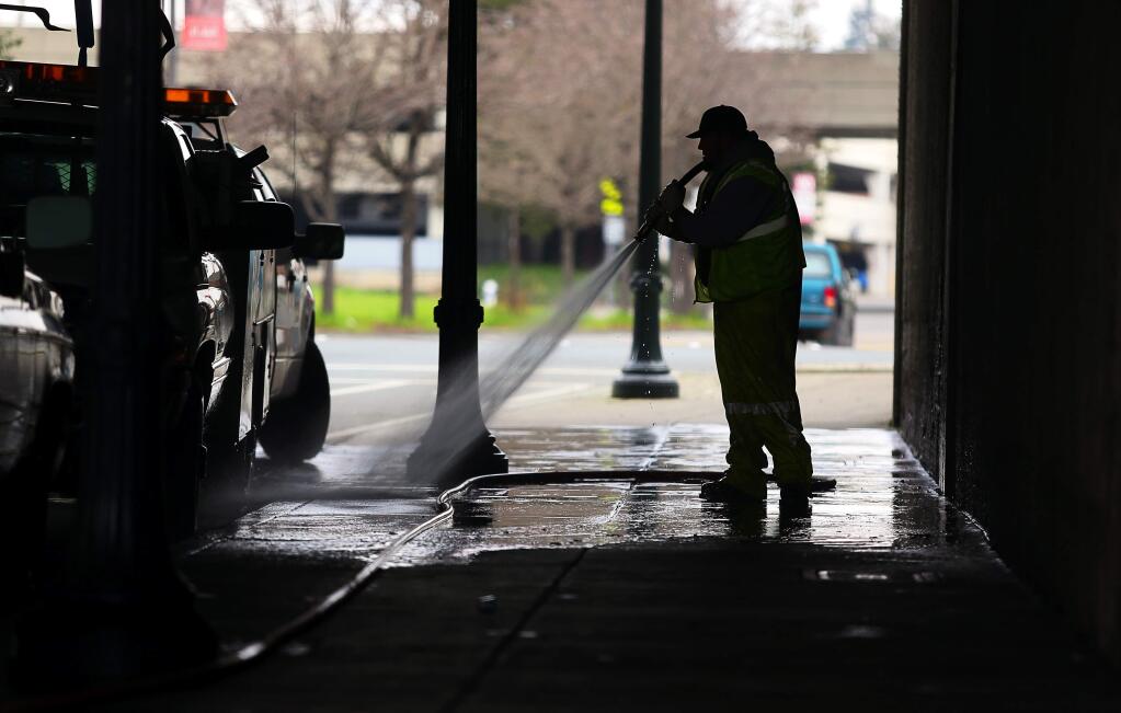 Deric Glenn of the Santa Rosa Public Works Department, pressure washes the sidewalk at the Sixth Street underpass Wednesday after a homeless encampment was removed by Santa Rosa police. (CHIRSTOPHER CHUNG / The Press Democrat)