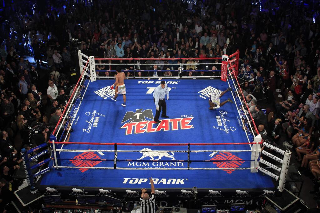 Manny Pacquiao, left, heads to a neutral corner after knocking down Timothy Bradley Jr. in the ninth round of their welterweight fight at MGM Grand Garden Arena in Las Vegas, Saturday, April 9, 2016. Referee Tony Weeks is at center. Pacquiao won the fight by unanimous decision. (Steve Marcus/Las Vegas Sun via AP)