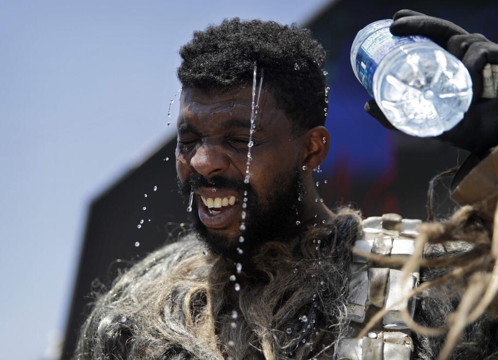 Xaviere Coleman pours water over his head to cool off in a Wookiee costume along the Las Vegas Strip, Tuesday, June 20, 2017, in Las Vegas. Coleman was taking a break from posing for photographs with tourists. The first day of summer is forecast to bring some of the worst heat the southwestern U.S. has seen in years. (AP Photo/John Locher)
