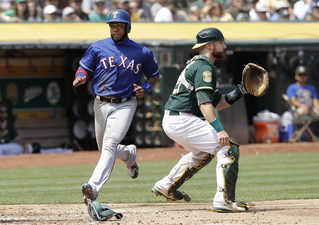 The Texas Rangers' Elvis Andrus, left, scores a run with Oakland Athletics catcher Jonathan Lucroy at right during the fifth inning in Oakland, Wednesday, Aug. 22, 2018. (AP Photo/Jeff Chiu)