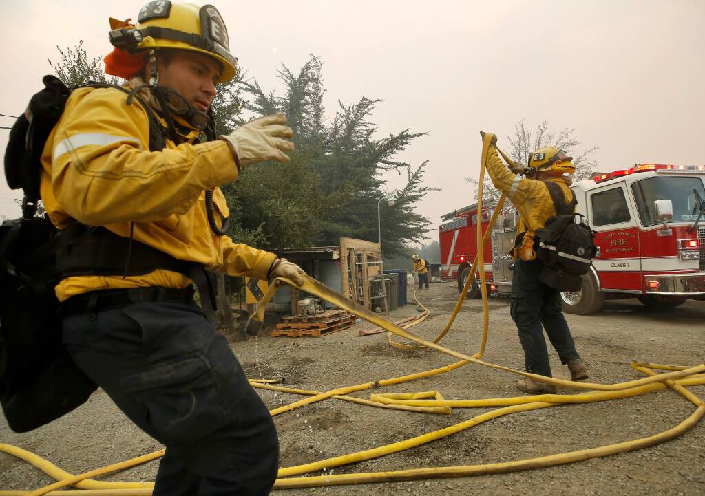 Santa Monica Fire Department firefighters Armando Reyes, left, and Andrew Klein quickly bundle their fire engine's hose to move to protect a different structure during the Kincade fire on Los Amigos Road in Windsor on Sunday, Oct. 27, 2019. (ALVIN JORNADA/ PD)