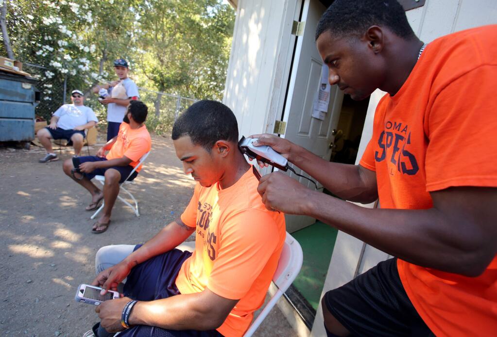 Sonoma Stompers Matt Hibbert, left, has his hair cut by teammate Roman Martinez, right, during the game against San Rafael Pacific held at Arnold Field in Sonoma Wednesday, July 23, 2014. (Crista Jeremiason / The Press Democrat)