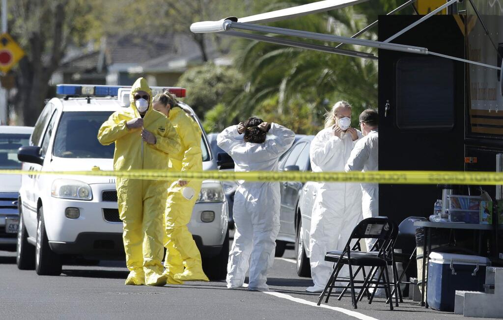Investigators put on protective suits before entering a home where four people were found dead, Thursday, March 23, 2017, in Sacramento, Calif. A suspect is being held in San Francisco. Police are not saying how the four were killed and are not immediately identifying the victims, including their genders and ages .(AP Photo/Rich Pedroncelli)