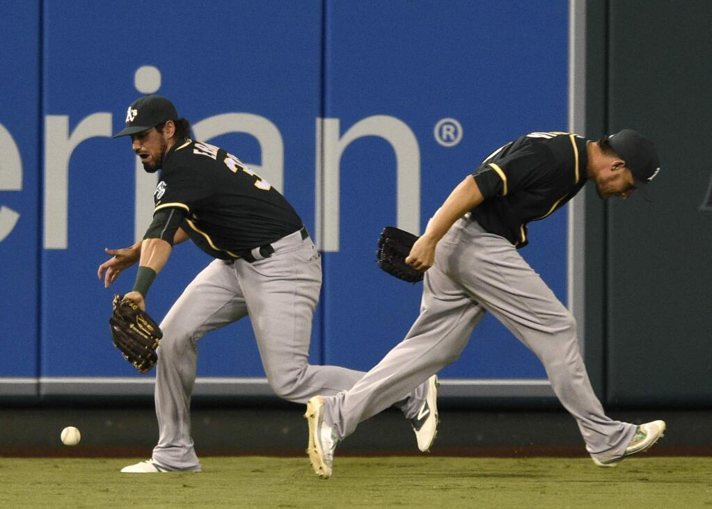 Oakland Athletics center fielder Brett Eibner, left, is unable to catch a fly ball to center field for a double from the Los Angeles Angels' Kole Calhoun, not pictured, as Danny Valencia, right, attempts to duck out of the way during the first inning Tuesday, Sept. 27, 2016. (AP Photo/Kelvin Kuo)