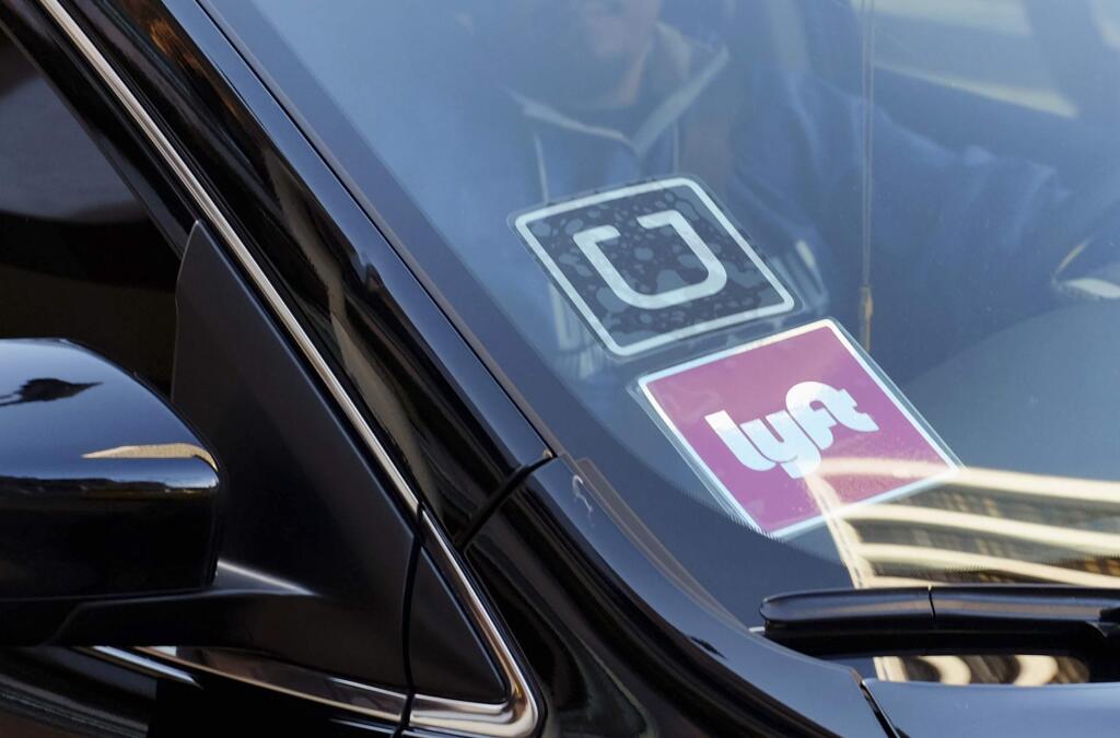 FILE - In this Jan. 12, 2016, file photo, a driver displaying Lyft and Uber stickers on his front windshield drops off a customer in downtown Los Angeles. (AP Photo/Richard Vogel, File)